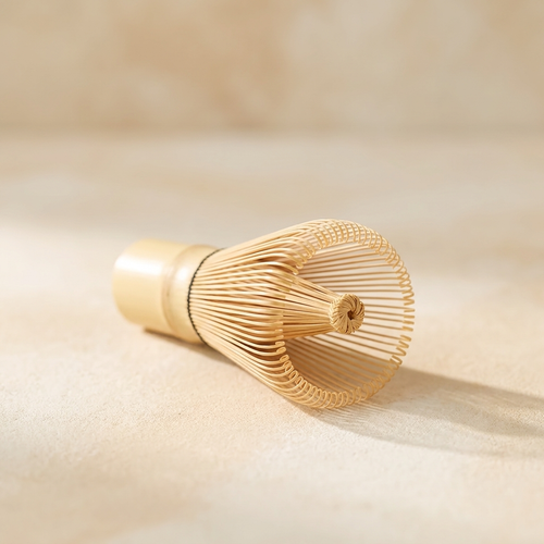 Wrenly bamboo matcha whisk (chasen), pale white bamboo with about one hundred fine tines on a cream surface